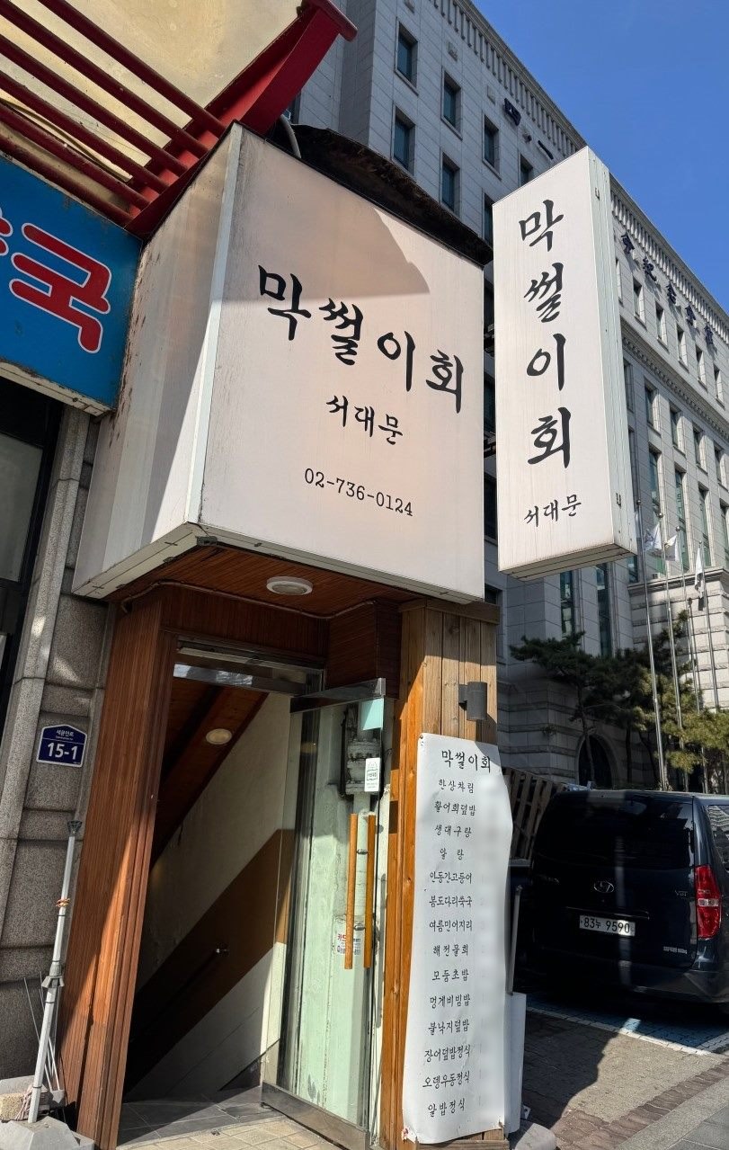 막썰이회 서대문 입구 — 서대문역 인근, 간판에 가게 이름과 전화번호가 적혀 있고 옆에 메뉴판이 붙어 있습니다